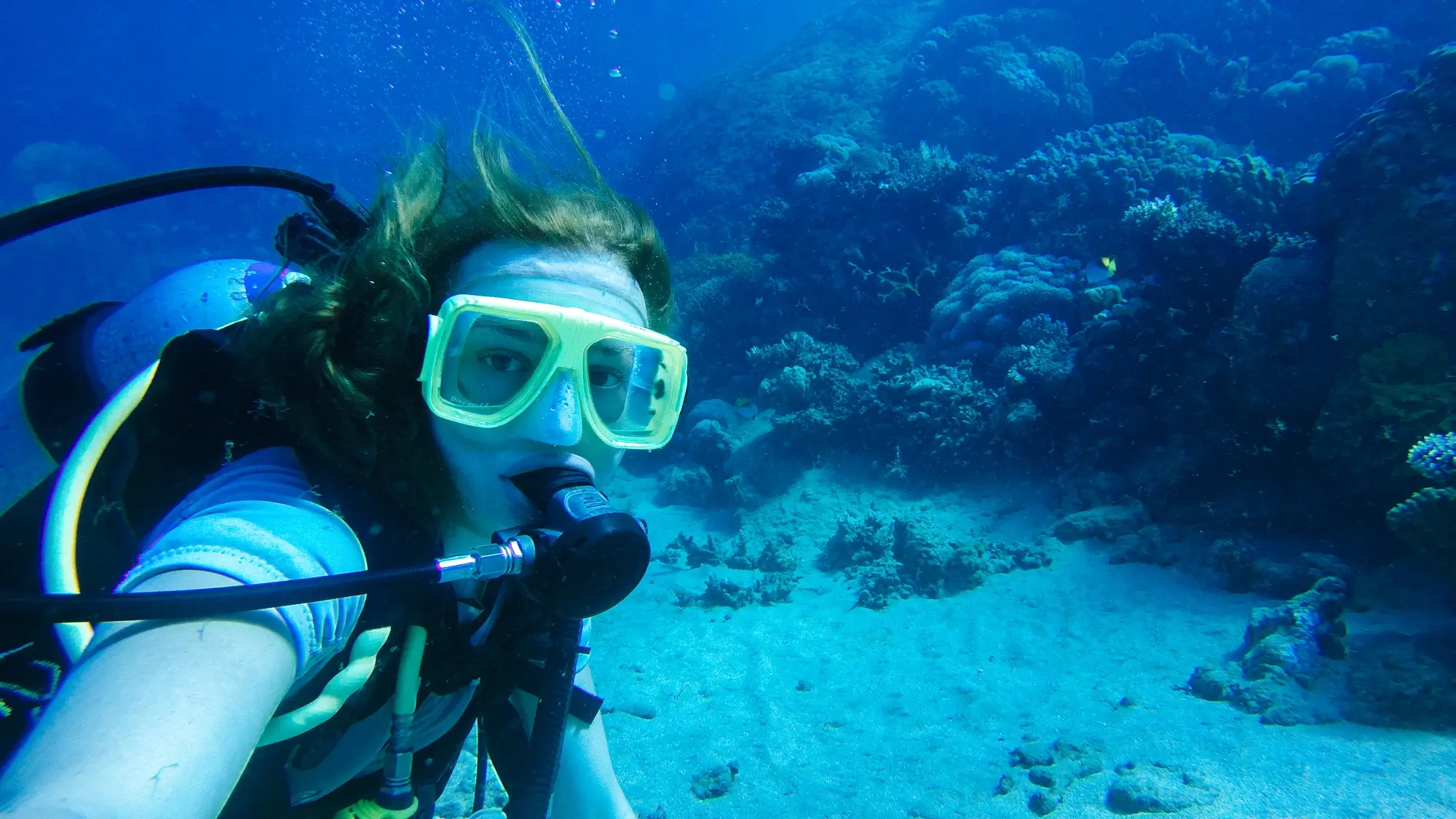 Girl scuba diving in front of corals