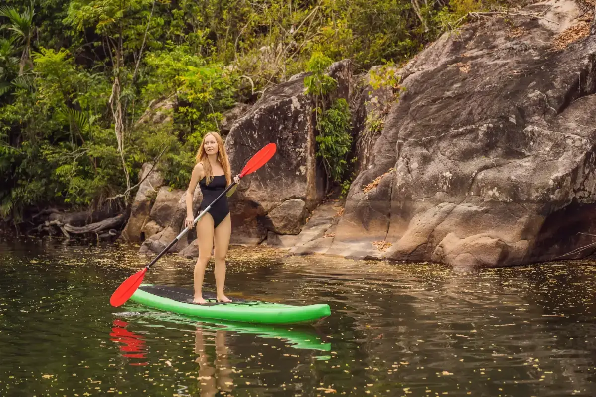 SUP Stand up paddle board woman paddle boarding on lake standing happy on paddleboard on blue water.